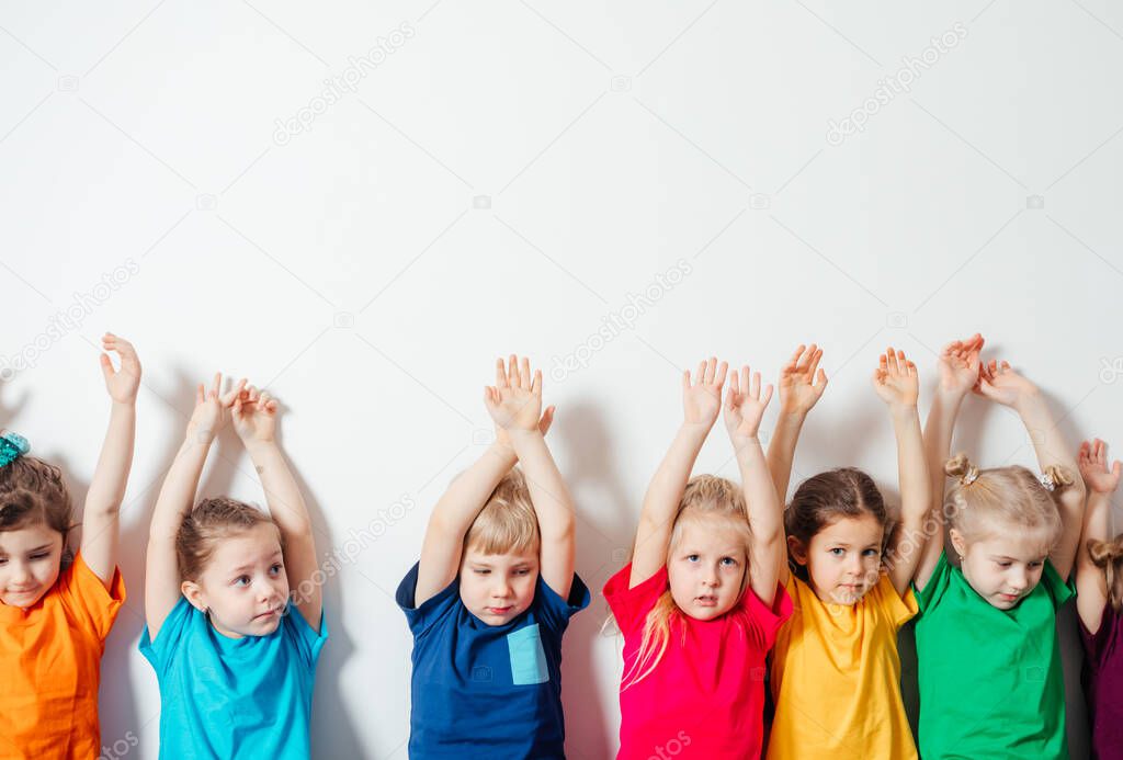 Children holding hands up on white wall background