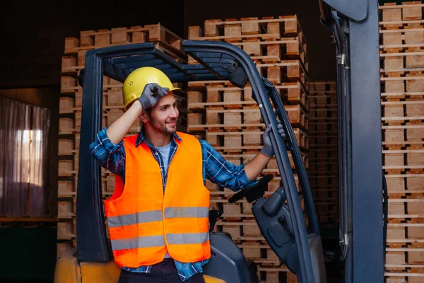 Sorrindo homem posando perto empilhadeira industrial no armazém — Fotografia de Stock