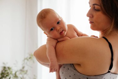 Işıklı beyaz arka planda çıplak yeni doğmuş bir anne.