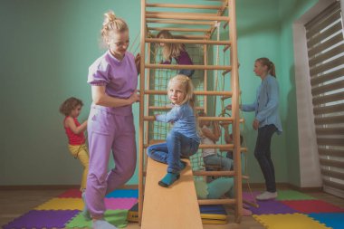 Öğretmen anaokulunda aktif oyunlar sırasında çocuklara destek oluyor