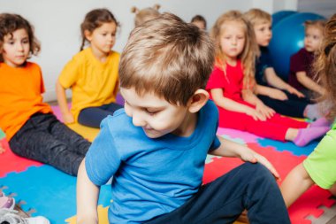 Meraklı anaokulu çocuğu grup jimnastiğinin keyfini çıkarıyor.