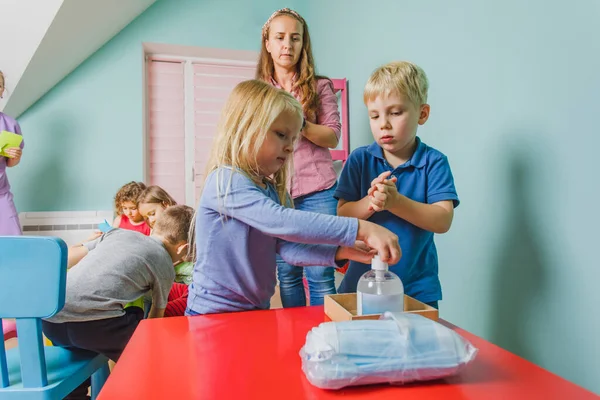 Enseignant montre aux petits enfants comment désinfecter les mains — Photo