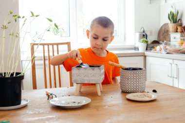 Küçük bahçıvan seramik kapta toprağı gevşetiyor.