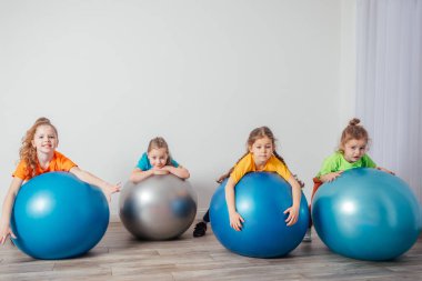 Tatlı çocuklar büyük spor topları üzerinde dengede duruyorlar.