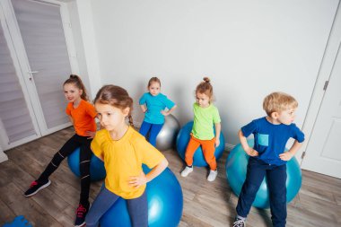 Tatlı çocuklar büyük spor topları üzerinde dengede duruyorlar.