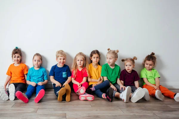 Bambini allegri seduti su un pavimento vicino al muro — Foto Stock