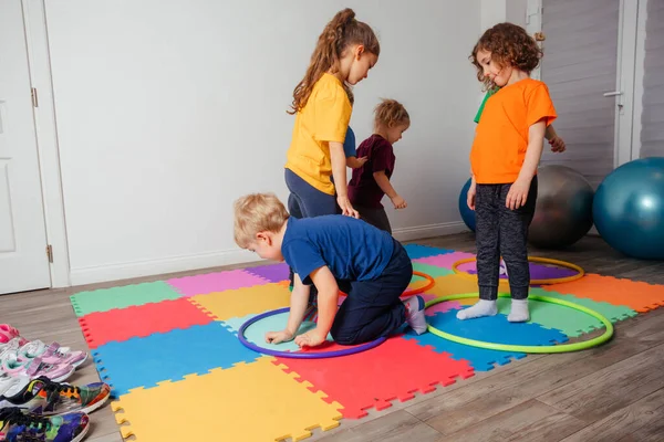 Los niños corriendo y saltando alrededor de aros multicolores en el suelo — Foto de Stock