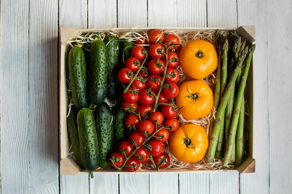 Delivery of fresh tomatoes and cucumbers in a wooden box — Stock Photo, Image