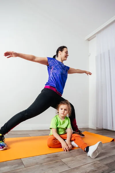 Lindo niño pequeño se aburre mientras la madre hace yoga por la mañana — Foto de Stock