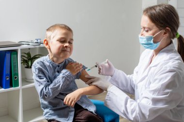 Rutin aşılar yapılırken sevimli, cesur anaokulu çocuğunun portresi.