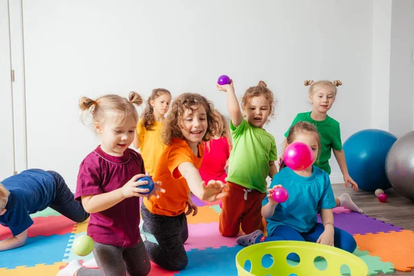 Счастливые дети бросают мячи в пластиковую корзину — стоковое фото