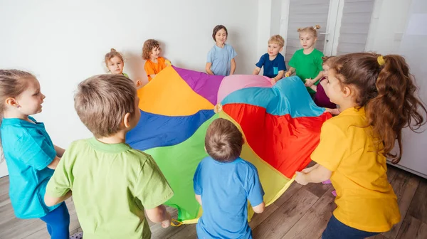 Děti strečink barevný padák pro zábavu týmové hry — Stock fotografie