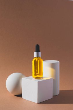 Beyaz küp podyum, üzerinde gerekli yağ şişesi var.