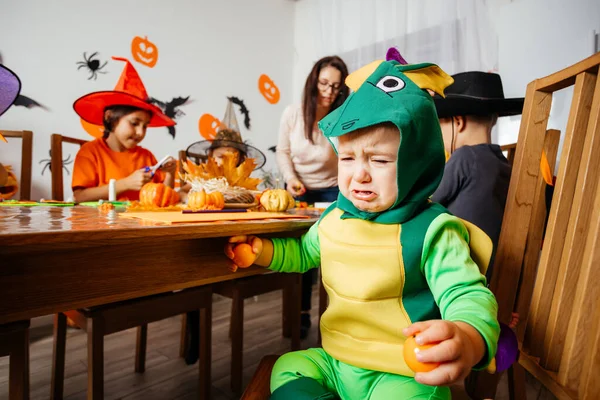Mały chłopiec w zielonym fantazyjnym stroju siedzi i płacze — Zdjęcie stockowe
