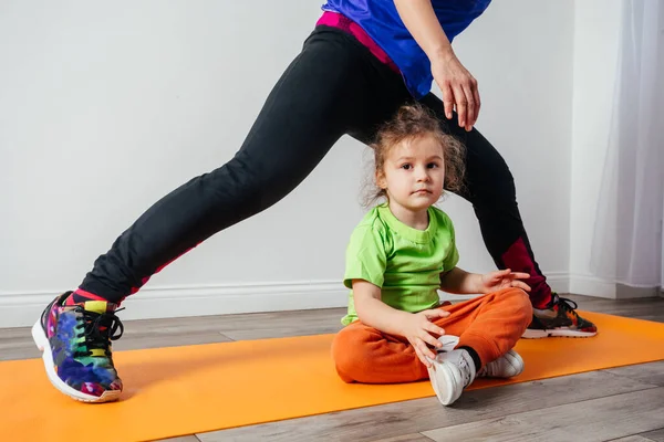 Lindo niño pequeño se aburre mientras la madre hace yoga por la mañana — Foto de Stock