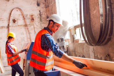 Genç işçiler ahşap fabrikasında tahta kesiyorlar.