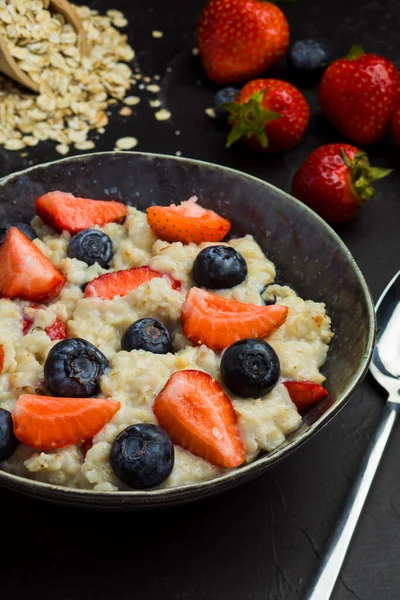 The concept of a healthy breakfast of oatmeal with strawberries and blueberries — Stock Photo, Image