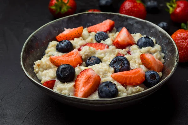 The concept of a healthy breakfast of oatmeal with strawberries and blueberries — Stock Photo, Image