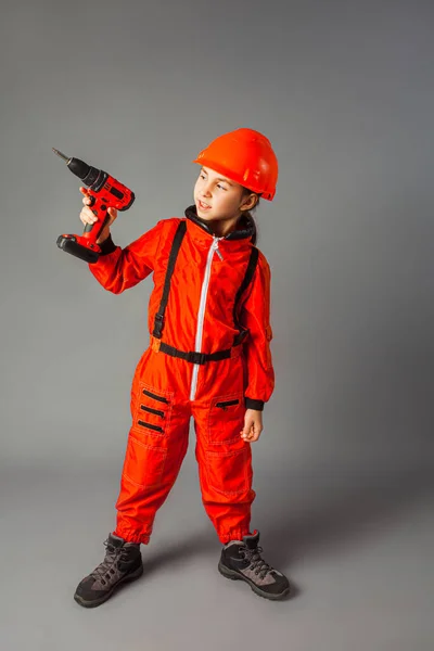 Kırmızı mühendislik üniforması giymiş küçük kız elinde bir tornavida tutuyor. — Stok fotoğraf