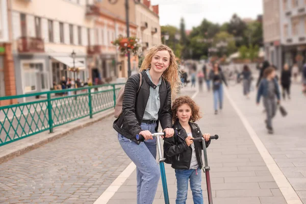 Szczęśliwa mama i córka stoją ze skuterami w mieście — Zdjęcie stockowe