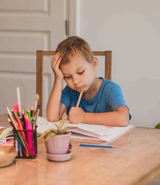 El chico cansado está haciendo los deberes solo en casa. — Foto de Stock