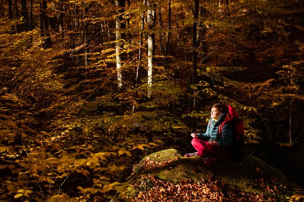 Жінка мандрівник в осінньому лісі сидить на камені — стокове фото