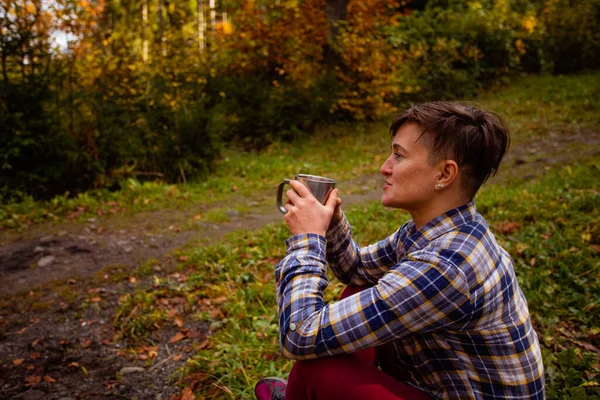 La mujer disfrutando de una bebida caliente en el bosque de otoño — Foto de Stock