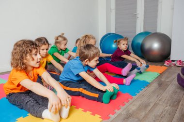 Anaokulunda beden eğitimi dersinde egzersiz yapan çocuklar
