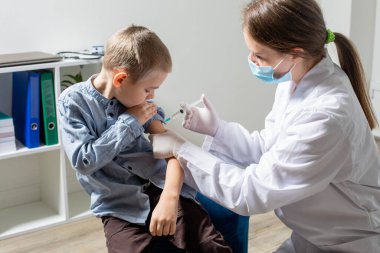 Rutin aşılar yapılırken sevimli, cesur anaokulu çocuğunun portresi.