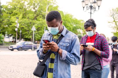 Maskeli insanlar kuyrukta bekleyip sosyal mesafeyi koruyorlar