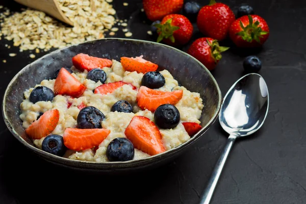 The concept of a healthy breakfast of oatmeal with strawberries and blueberries — Stock Photo, Image