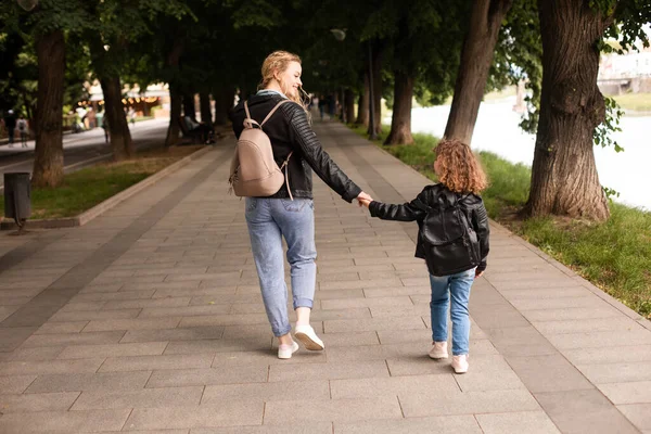 De moeder en het kleine meisje lopen samen langs de waterkant — Stockfoto