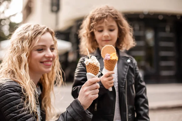 La mère et la fille heureuses tiennent la crème glacée tout en marchant — Photo