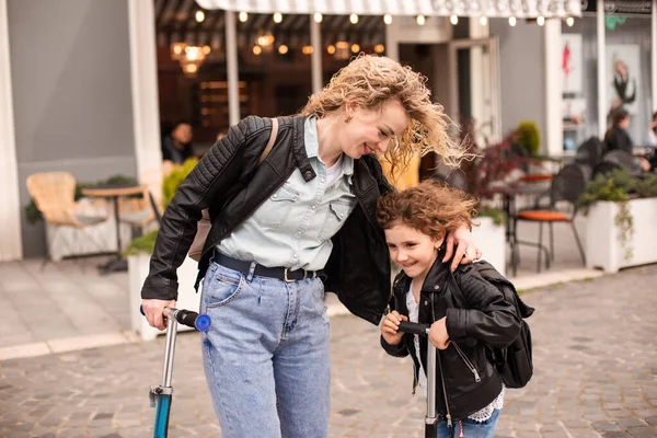 Identieke moeder en dochter met scooters in de stad — Stockfoto