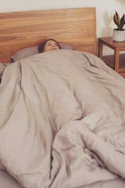 Tanımlanamayan eller battaniyeyi başının üstünde tutuyor.