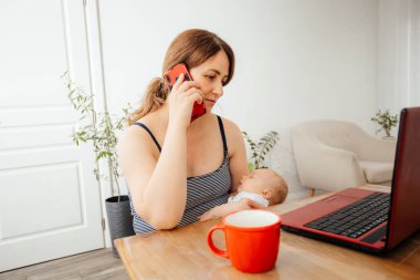 İş kadını uzaktan kumandayla yeni doğmuş bebeği tutuyor.