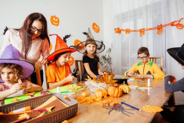 Öğretmen yaratıcı çocuklara kağıt yer imleri yapmaları için yardım ediyor