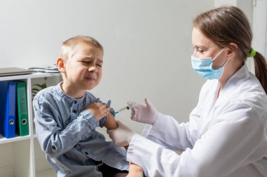 Rutin aşılar yapılırken sevimli, cesur anaokulu çocuğunun portresi.