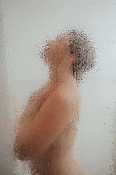 Showering woman behind glass door with water drops — Stock Photo, Image