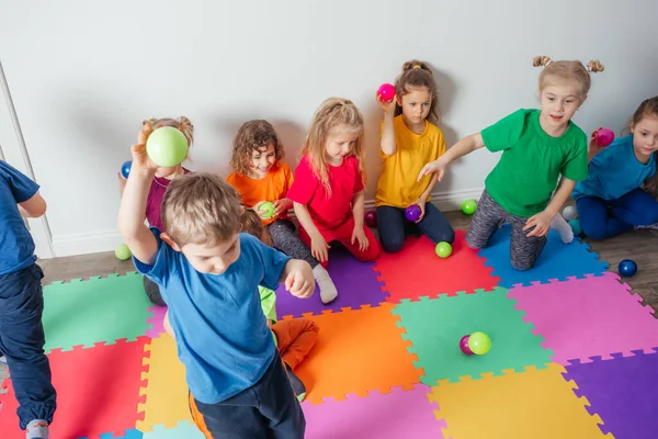 Энергичные молодые люди выбрасывают много разноцветных шаров — стоковое фото