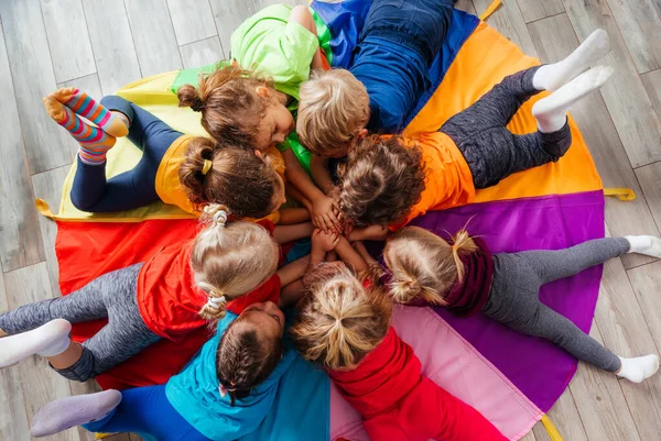 Vrolijke kinderen spelen team building games op een vloer — Stockfoto