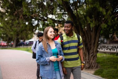 Arkadaşlarıyla parkta yürüyen ırklar arası bir çift.