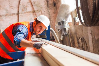 Genç işçiler ahşap fabrikasında tahta kesiyorlar.