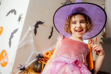 Pembe elbiseli ve cadı şapkalı sevimli kız.