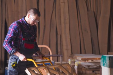 Tahta dekoratif elementleri el arabası kullanarak taşıyan bir adam.