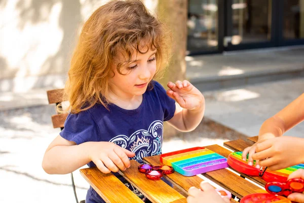 Coloré jouet anti-stress violon pousser pop il dans les mains des enfants — Photo