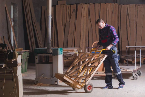 Человек, перевозящий деревянные декоративные элементы с помощью ручной тележки — стоковое фото