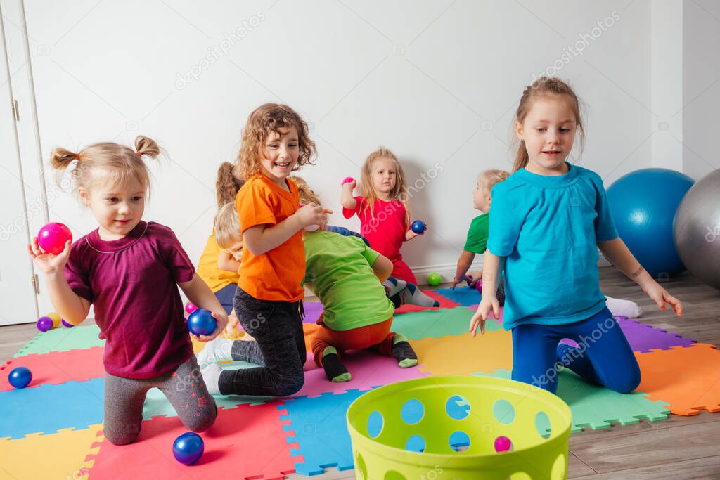 Happy kids throwing balls into plastic basket