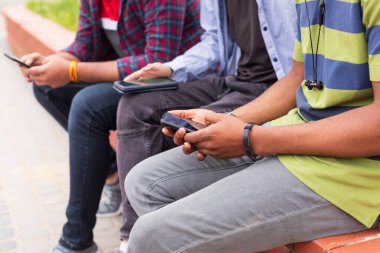 Yakından bakınca genç erkekler akıllı telefonlara bakıyor.