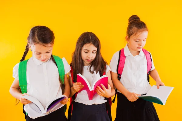 Malé školačky čtou knihy na žlutém pozadí. — Stock fotografie